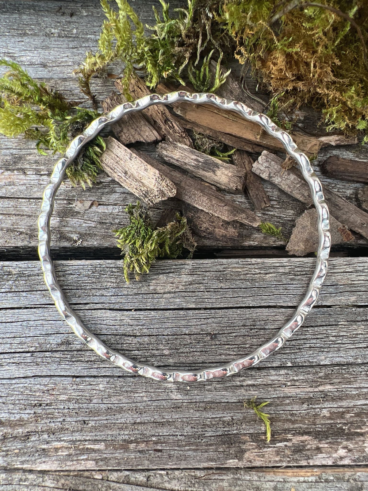 Handmade sterling silver ripple wave bangle 2.5mm on driftwood, overhead angle showing the full rippled wave outline