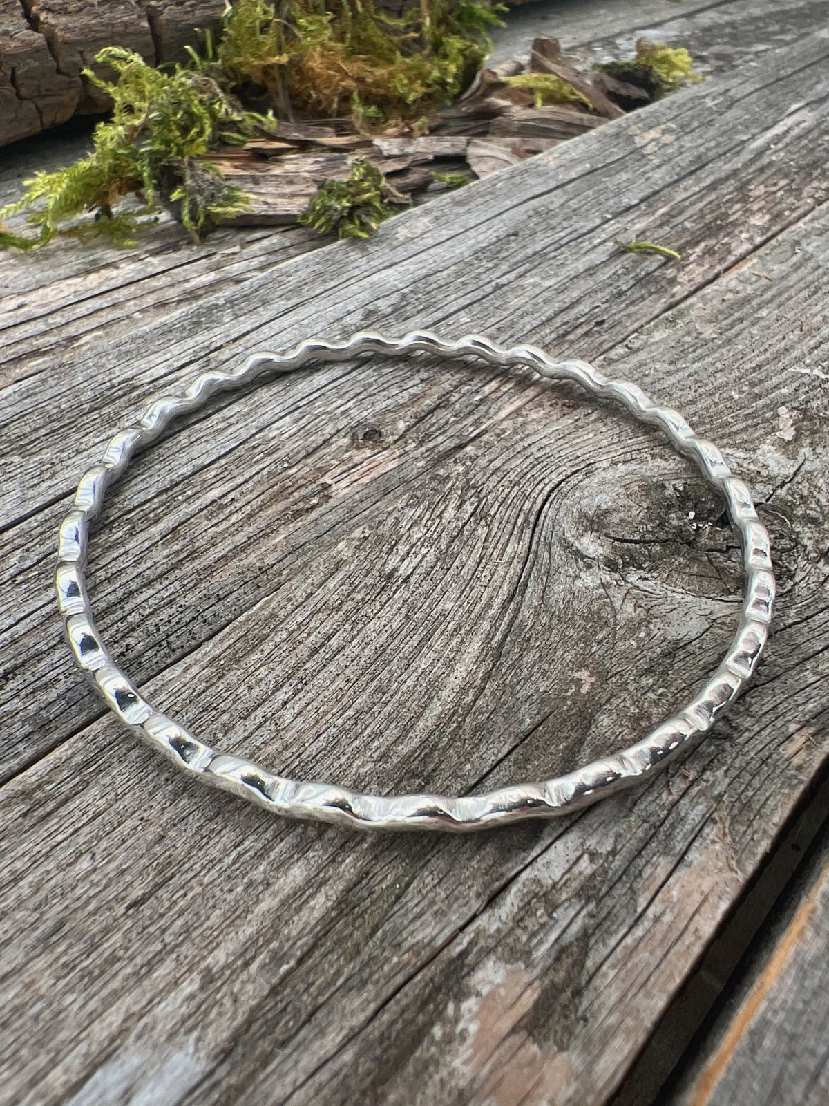Recycled sterling silver ripple wave bangle 2.5mm on weathered driftwood, handmade Isle of Wight jewellery