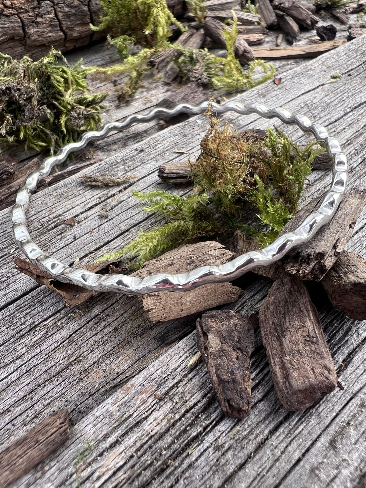 Recycled sterling silver ripple wave bangle 2.5mm on mossy driftwood, showing the textured rippled wave edge