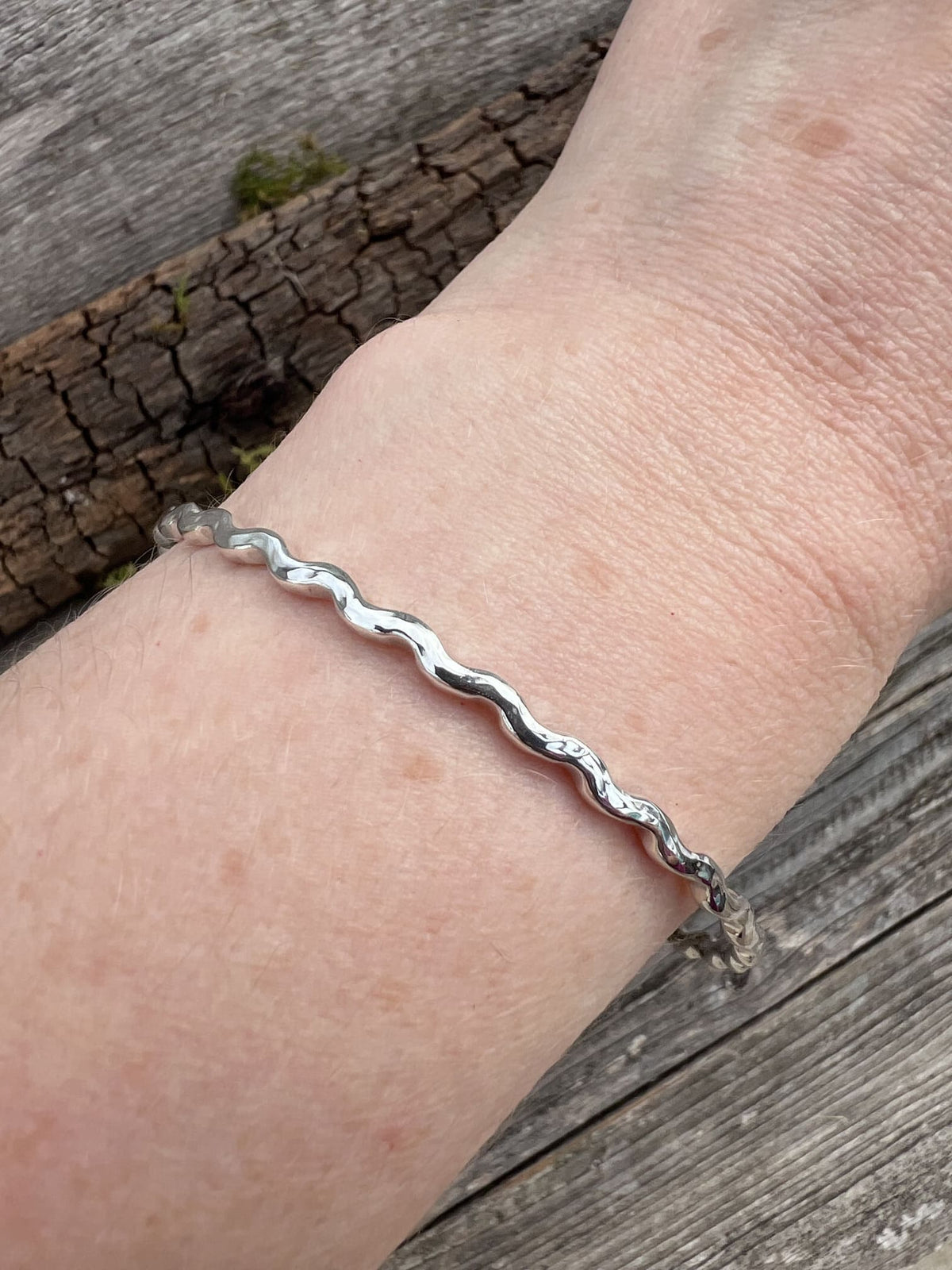 Sterling silver ripple wave bangle 2.5mm worn on a wrist, showing scale and the textured rippled wave form