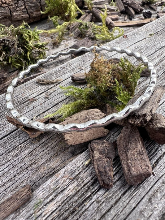 Recycled sterling silver ripple wave bangle 2.5mm on mossy driftwood, showing the textured rippled wave edge