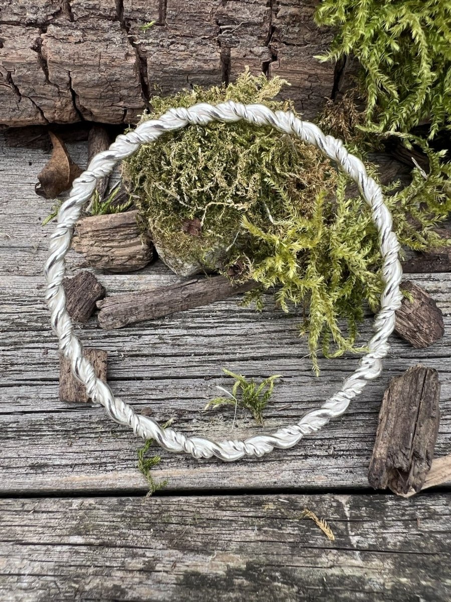 Recycled sterling silver rope twist bangle on weathered wood with moss, showing the twisted rope-style band