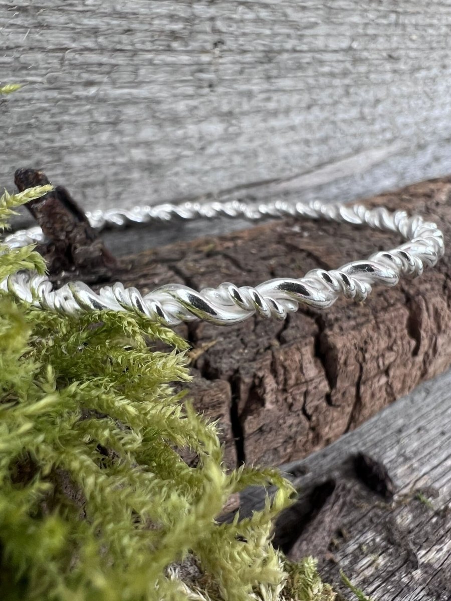 Recycled sterling silver rope twist bangle lying on weathered wood, handmade Isle of Wight jewellery