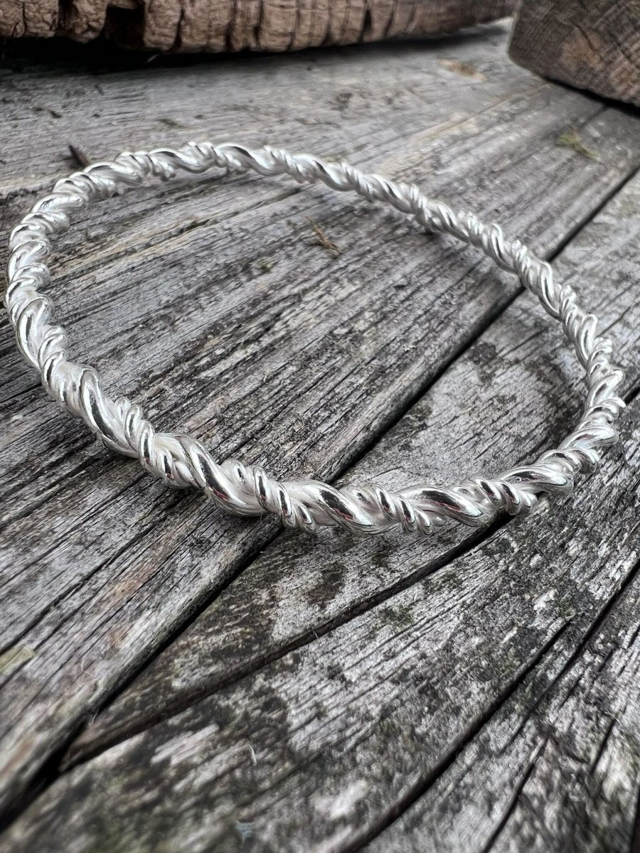 Recycled sterling silver rope twist bangle styled on weathered wood, showing the full circular twisted band