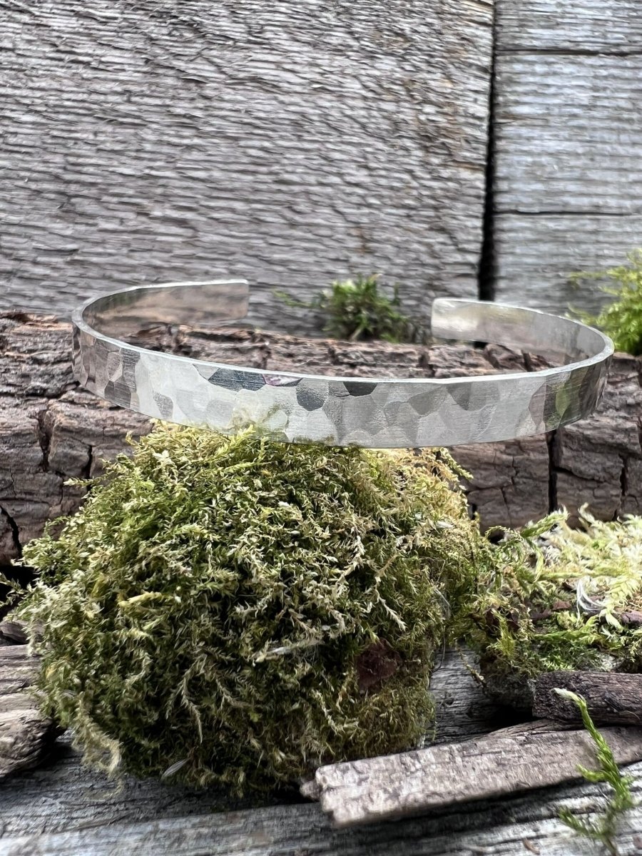 Recycled sterling silver Sierra textured torque bangle styled in a circular position on moss and weathered wood