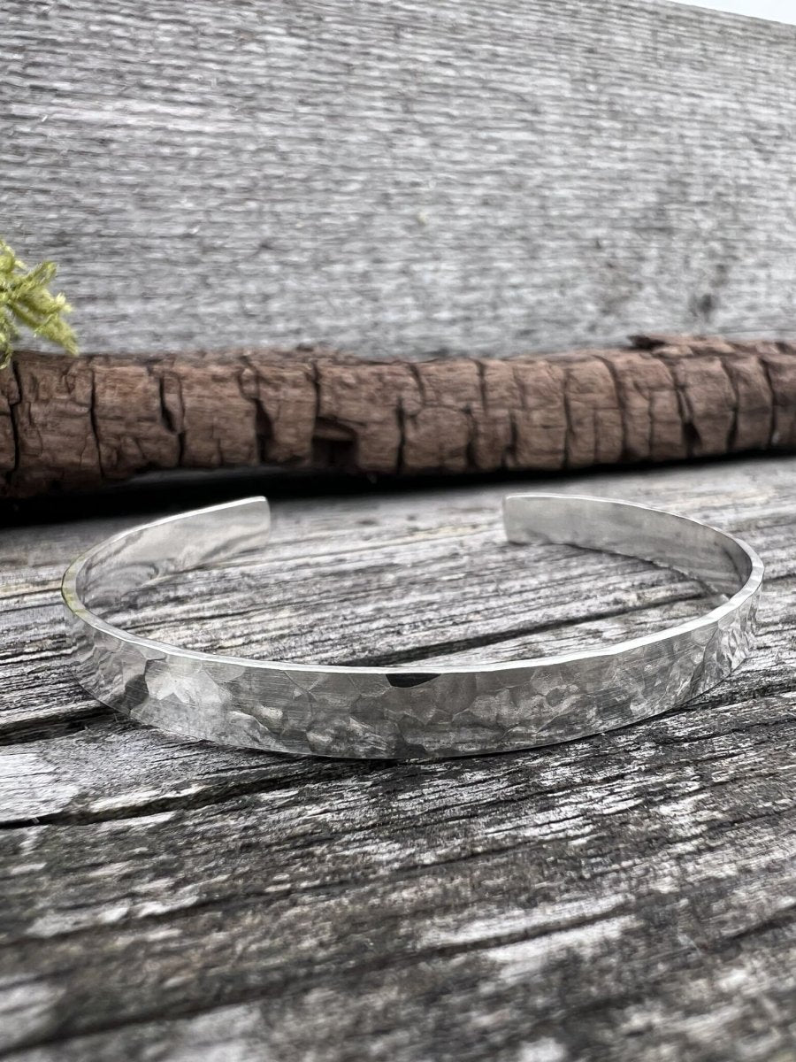Recycled sterling silver Sierra textured torque bangle on weathered wood, showing the heavily textured open band