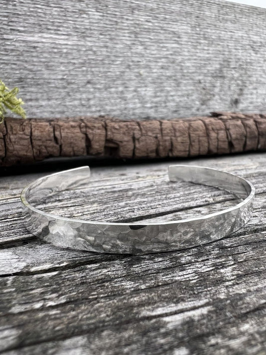 Recycled sterling silver Sierra textured torque bangle on weathered wood, showing the heavily textured open band