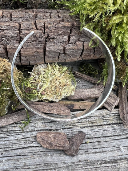 Recycled sterling silver Sierra textured torque bangle styled open on weathered wood with moss and bark pieces