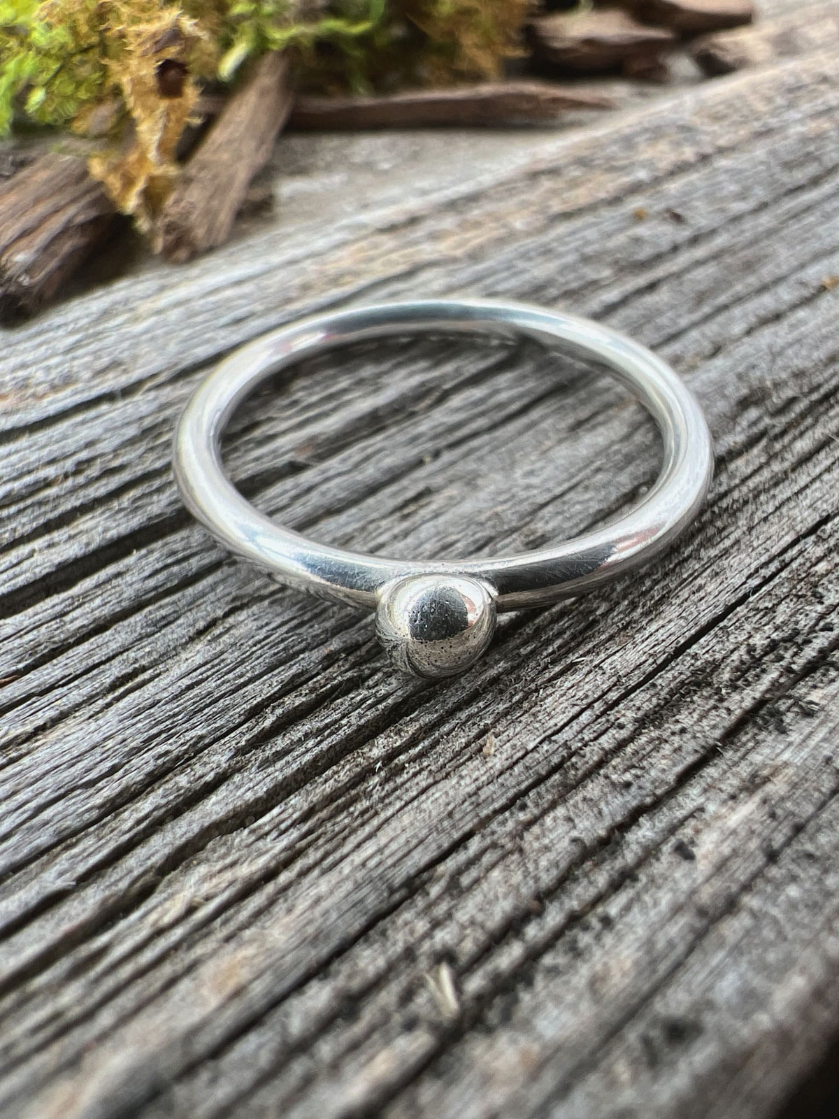 Recycled sterling silver single granule ring on weathered driftwood, handmade Isle of Wight jewellery