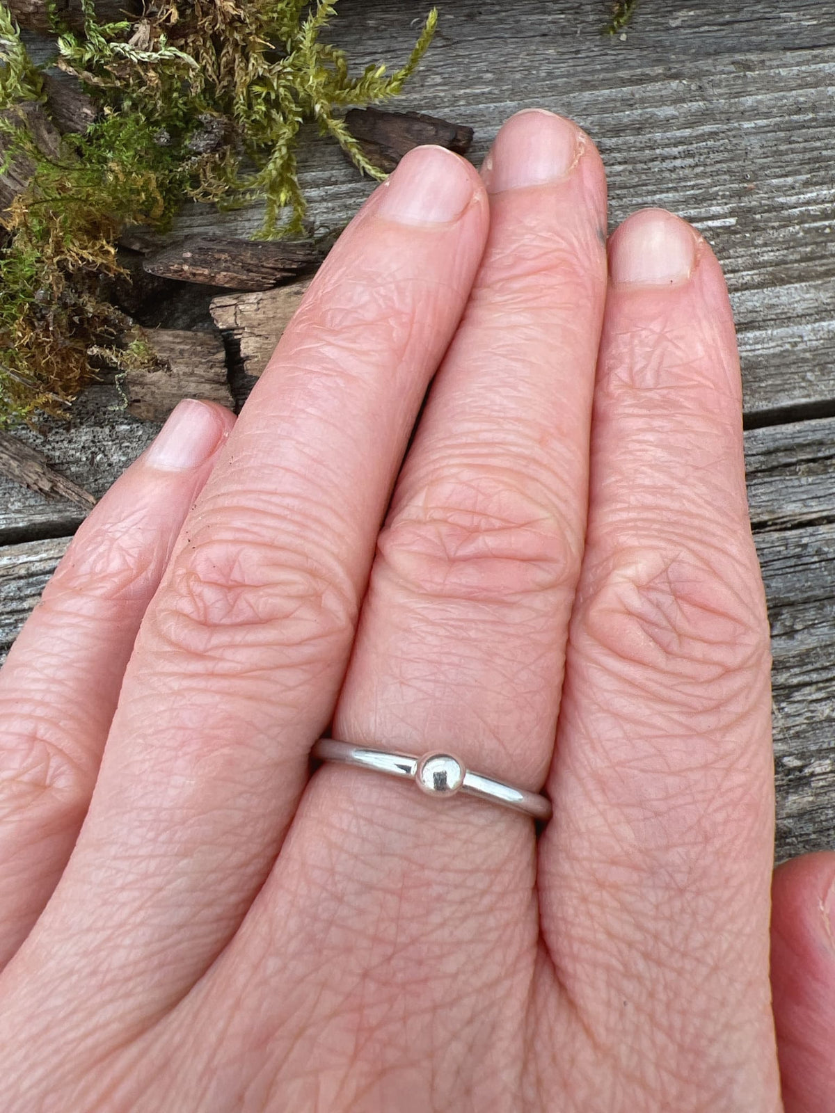 Sterling silver single granule ring worn on finger, showing scale and the delicate single silver bead on the band