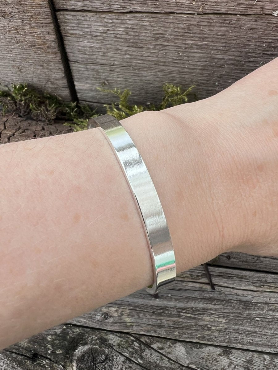 Recycled sterling silver Solstice sleek torque bangle worn on a wrist, showing the sleek polished band and fit