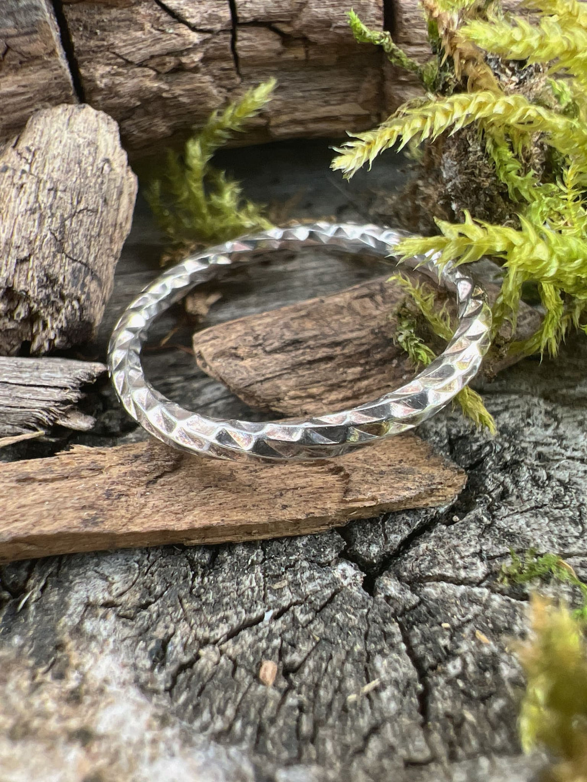 Recycled sterling silver sparkle cut ring on mossy driftwood, showing the light-catching faceted surface