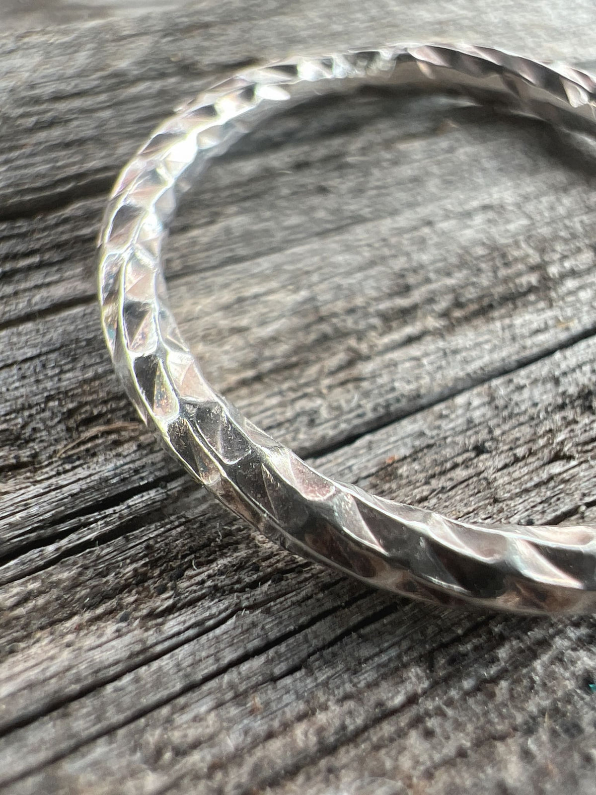 Close-up of a handmade sterling silver sparkle cut ring, showing the multiple faceted cuts along the band surface