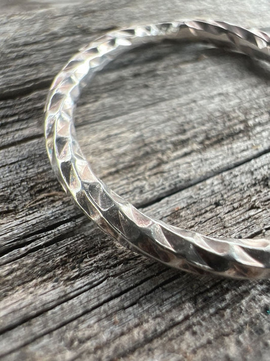 Close-up of a handmade sterling silver sparkle cut ring, showing the multiple faceted cuts along the band surface