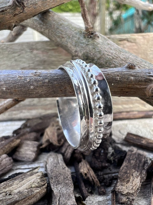 Recycled sterling silver spinner ring with beaded and plain bands on a wooden branch, showing the layered multi-band design