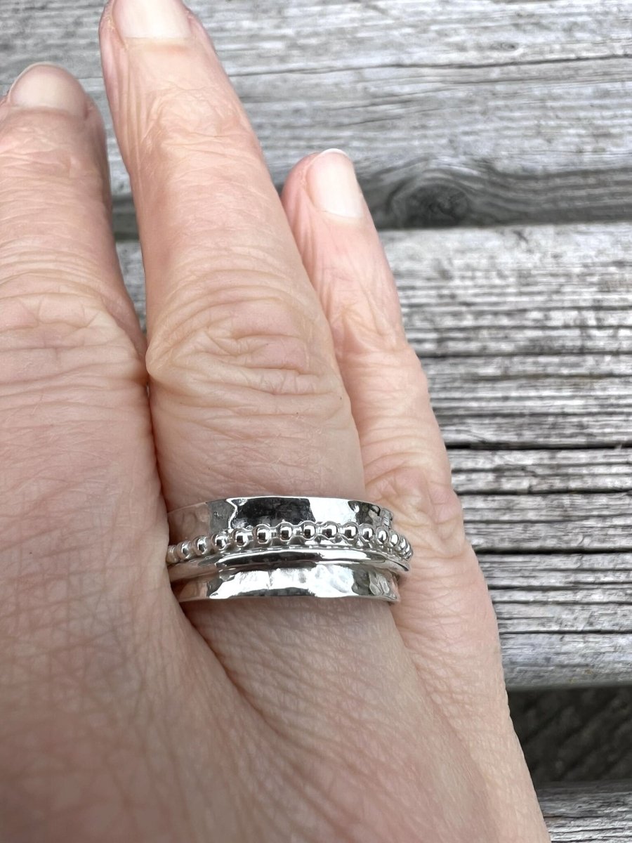 Sterling silver beaded and plain spinner ring worn on a finger, showing the stacked spinning bands and scale on the hand