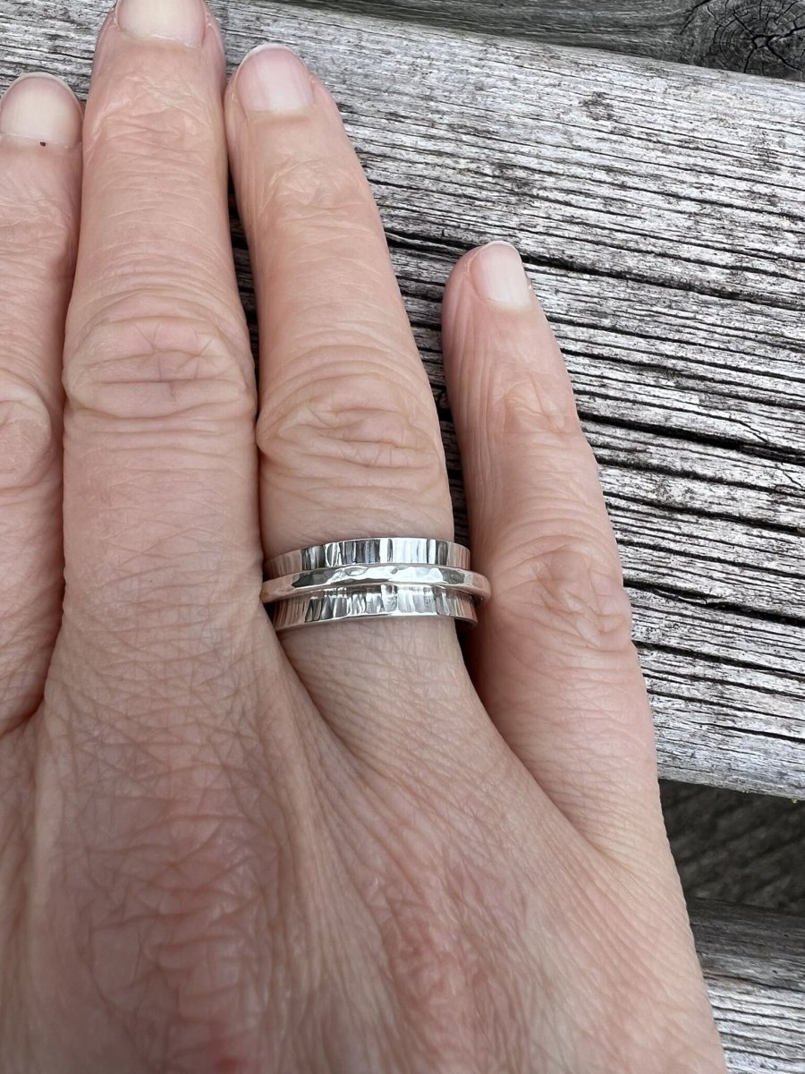 Sterling silver spinner ring with hammered band worn on a finger, showing scale and how the outer ring sits on the hand