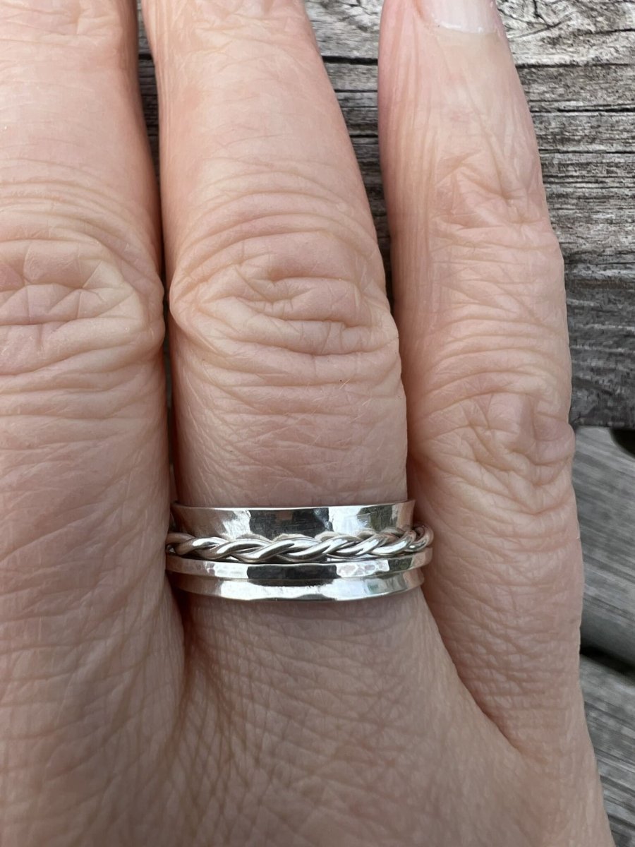 Sterling silver spinner ring with twisted and textured bands worn on a finger, showing scale and the decorative spinning elements