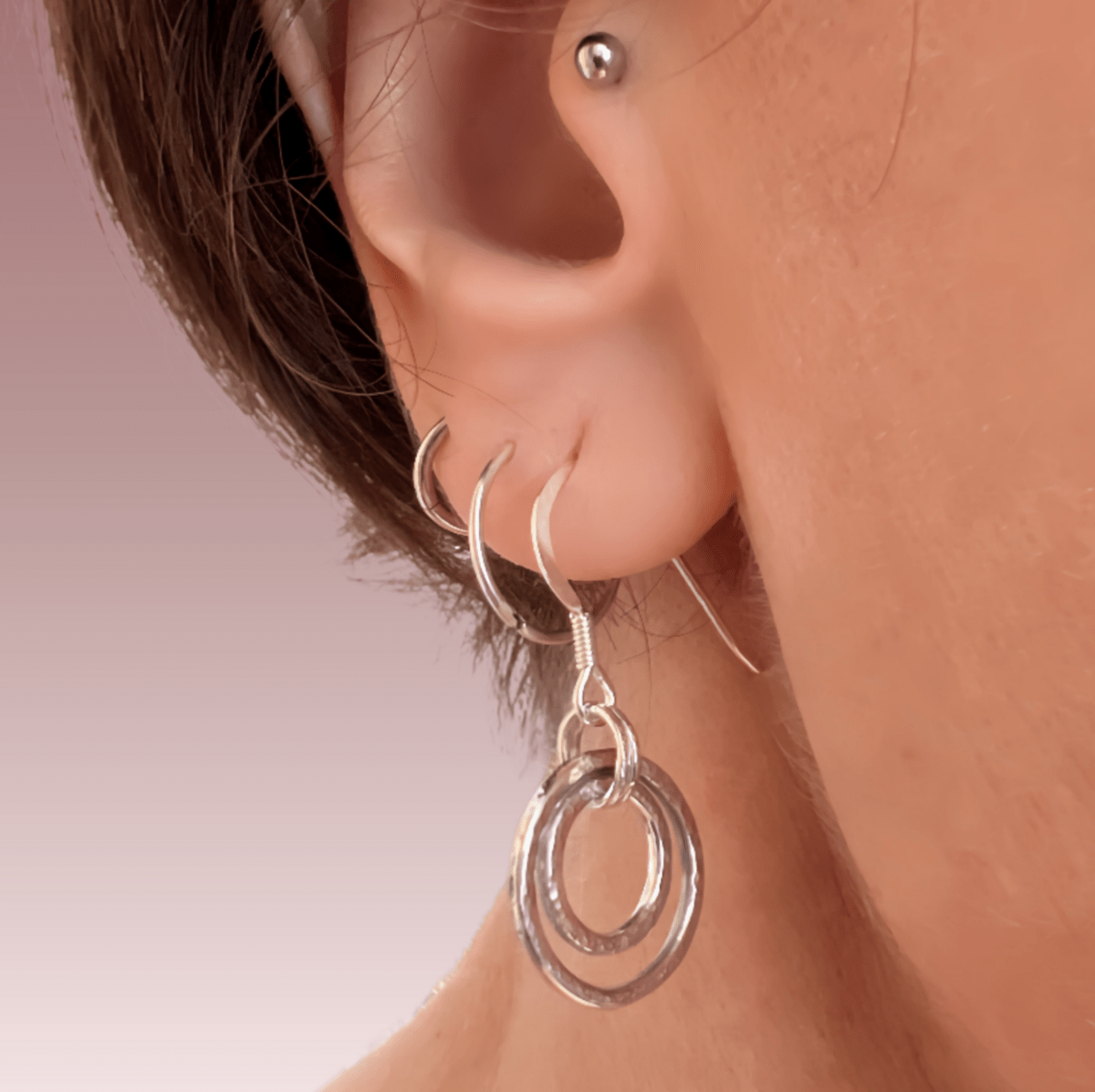 Sterling silver harmonic circles earrings worn in ear, showing how the concentric circle pendant hangs and the drop length