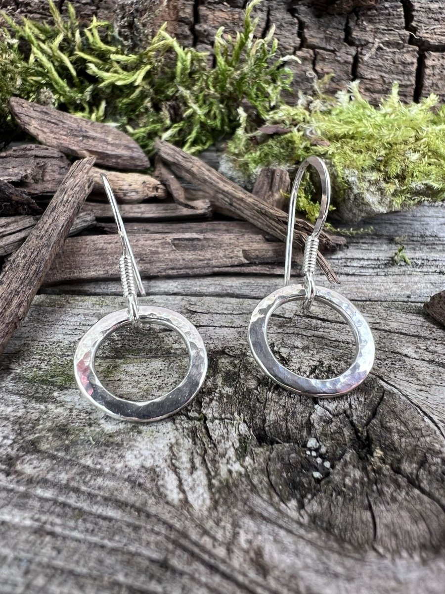 Recycled sterling silver radiant circle earrings styled on mossy weathered wood, showing the delicate circle drop design