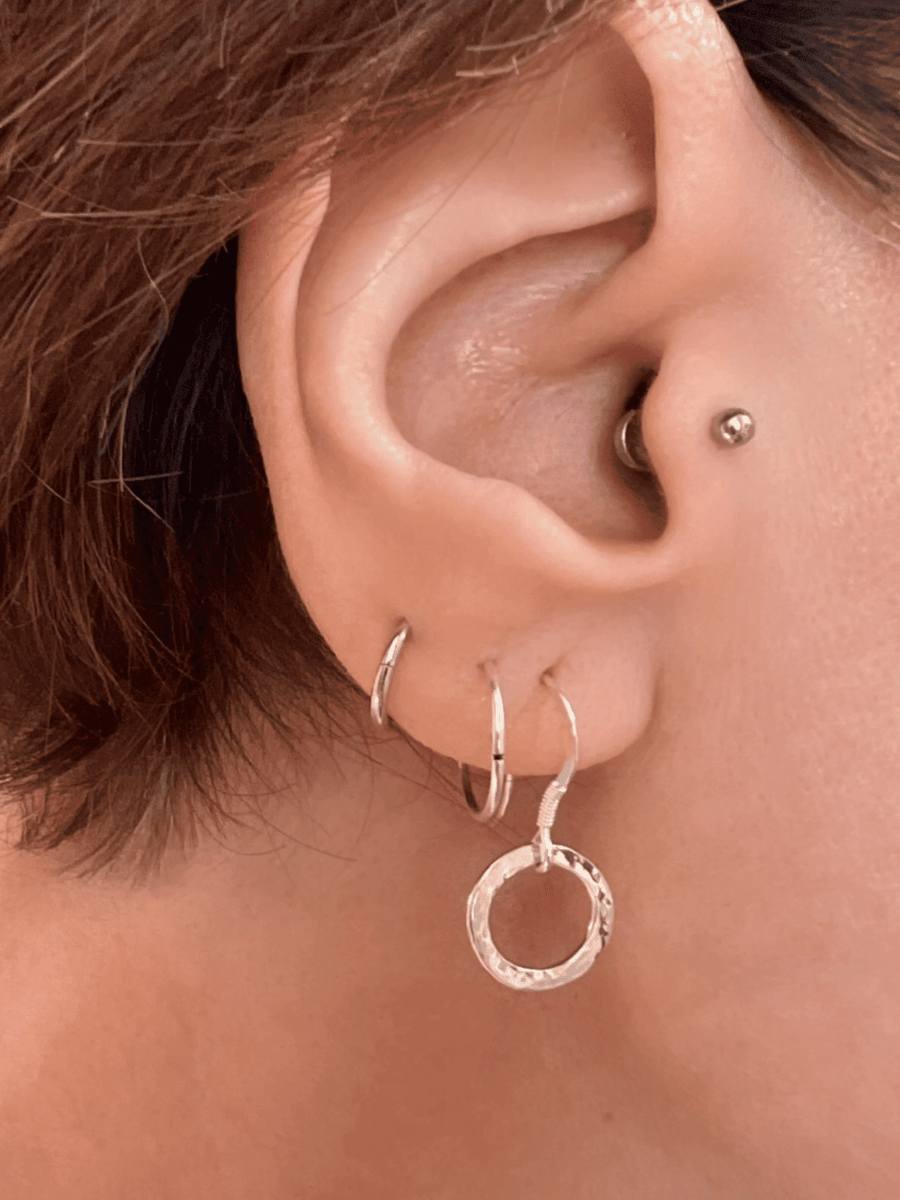 Sterling silver radiant circle drop earrings worn in ear, showing scale and how the open circle design sits