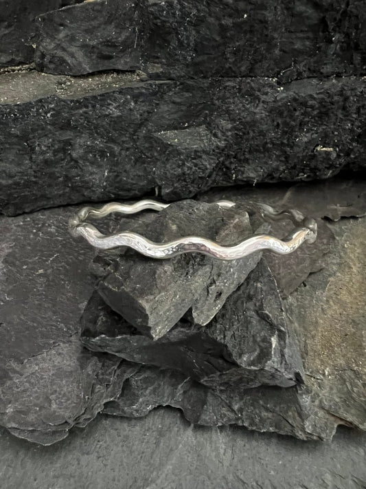 Sterling Silver Textured Wave Bangle (3.5 mm) Sat on Pieces of Charcoal