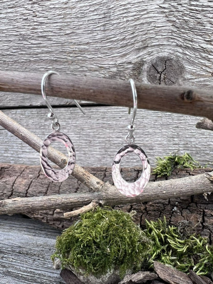 Handmade sterling silver textured oval earrings hanging from wooden branch with moss
