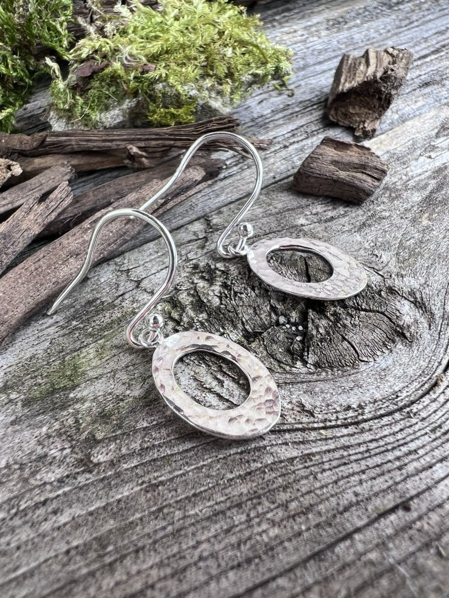 Recycled sterling silver textured oval drop earrings on weathered wood, showing the hammered open oval design
