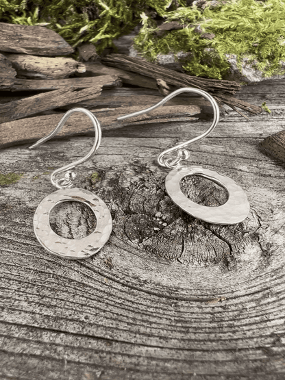 Recycled silver textured oval drop earrings styled on weathered wood, showing both earrings together with natural textures