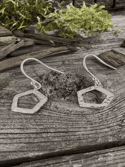 Recycled silver textured pentagon drop earrings on mossy weathered wood, both earrings together with geometric shapes