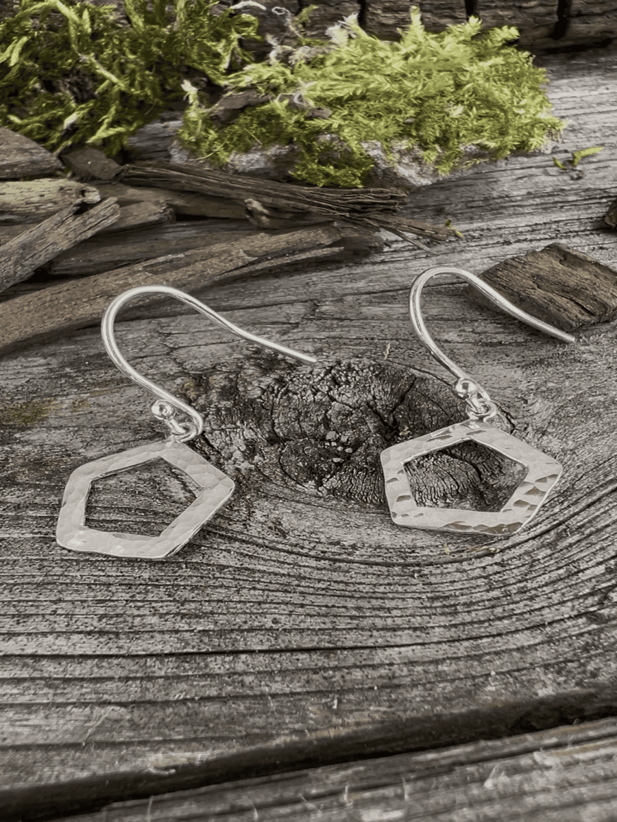 Recycled silver textured pentagon drop earrings on mossy weathered wood, showing both earrings together with the geometric shapes