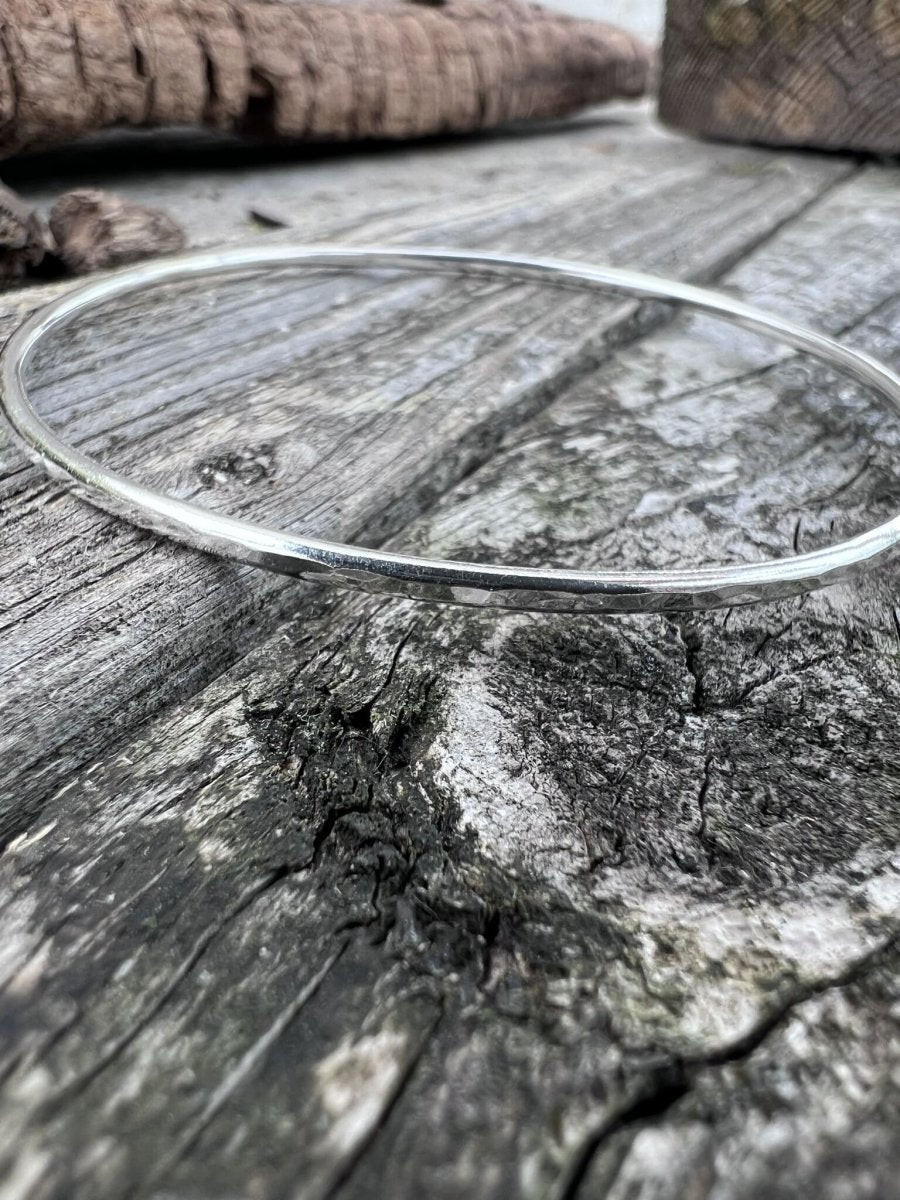 Recycled sterling silver textured round bangle, 2mm, on weathered wood, showing the fine hammered band