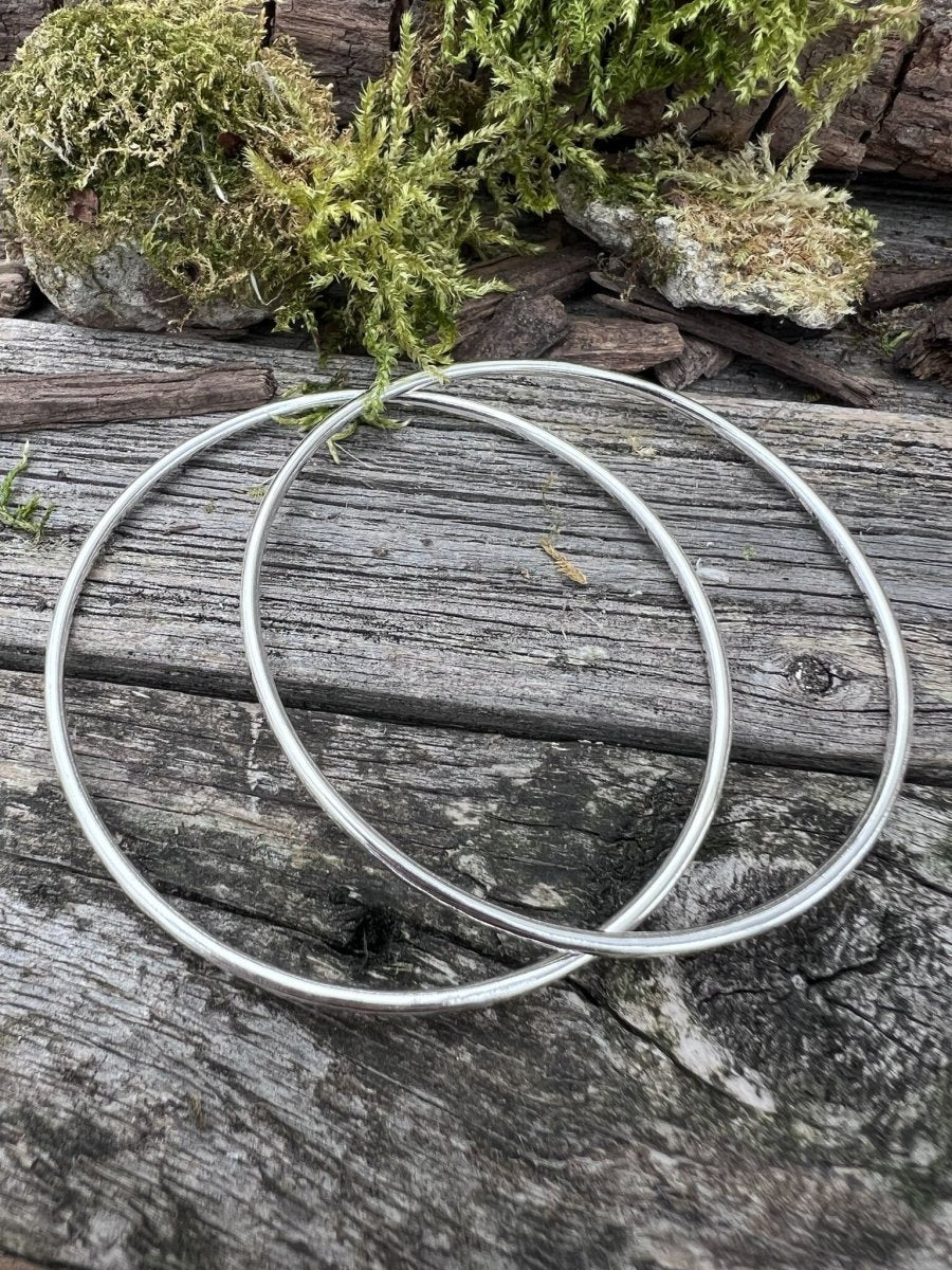 Two recycled sterling silver 2mm textured round bangles styled together on weathered wood