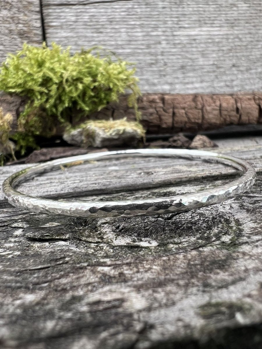 Recycled sterling silver 3.5mm textured round bangle lying flat on weathered wood