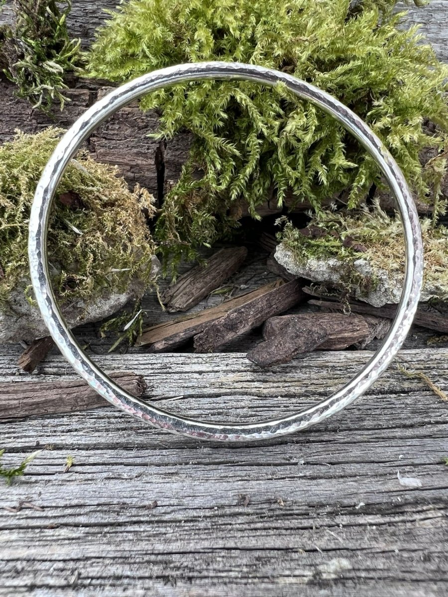 Recycled sterling silver textured round bangle, 3.5mm, on weathered wood with moss, showing the hammered band