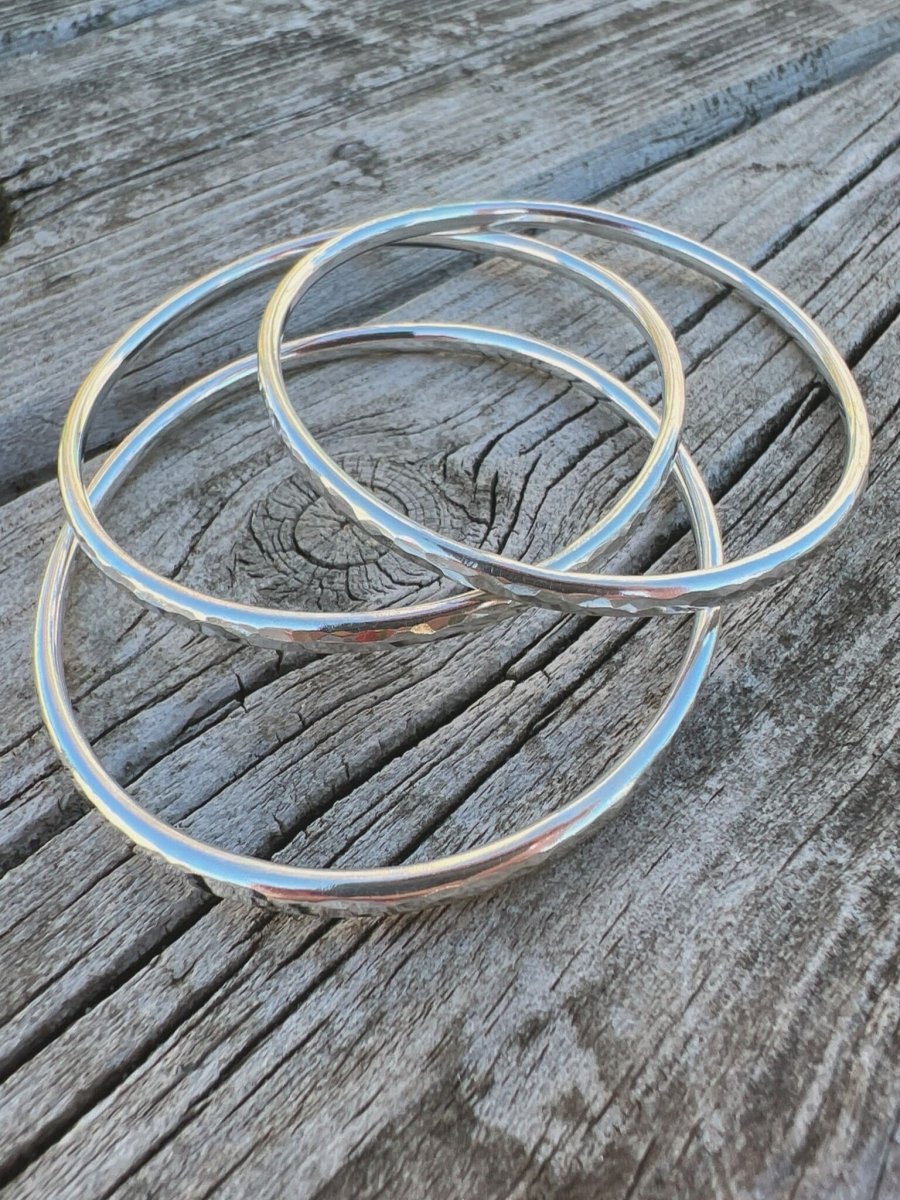 Recycled sterling silver textured round bangles, 3mm, on weathered wood, showing three hammered bands together