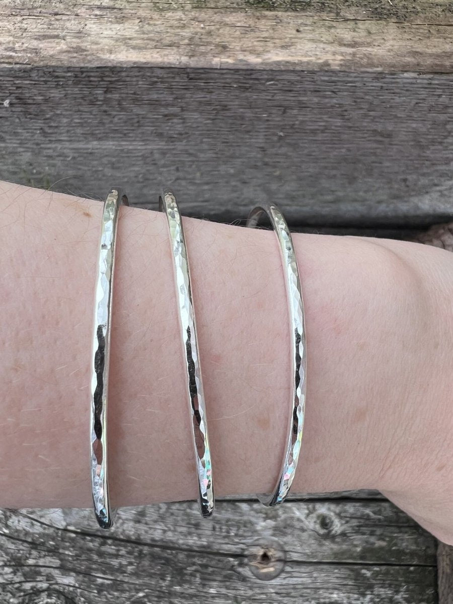 Three recycled sterling silver 3mm textured round bangles worn on a wrist, showing scale and stacked fit