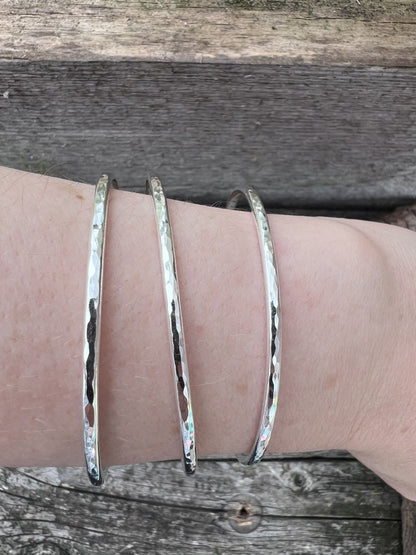 Three recycled sterling silver 3mm textured round bangles worn on a wrist, showing scale and stacked fit