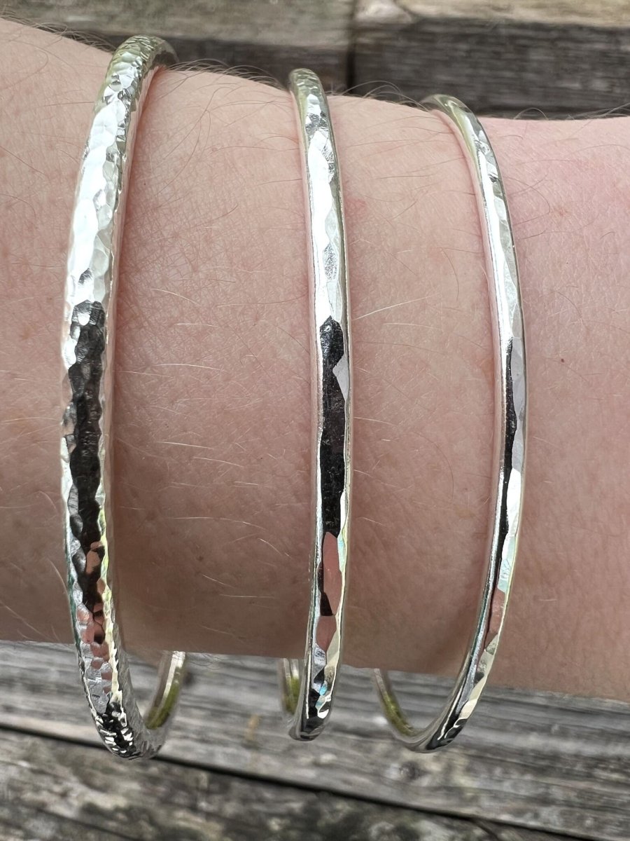 Three recycled sterling silver textured round bangles stacked on a wrist, showing how different sizes layer together