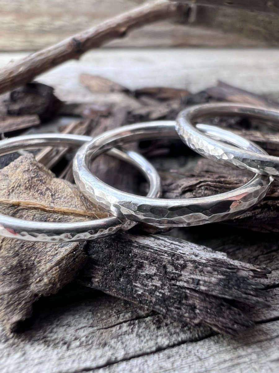 Multiple handmade silver textured stacking rings viewed from above on woos chips, showing the collection