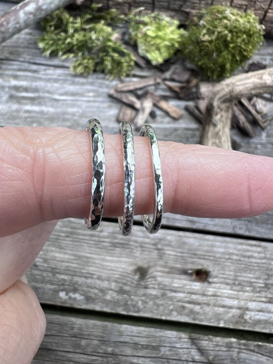 Three textured sterling silver stacking rings worn together on a finger, showing how they layer and stack