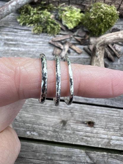 Three textured sterling silver stacking rings worn together on a finger, showing how they layer and stack