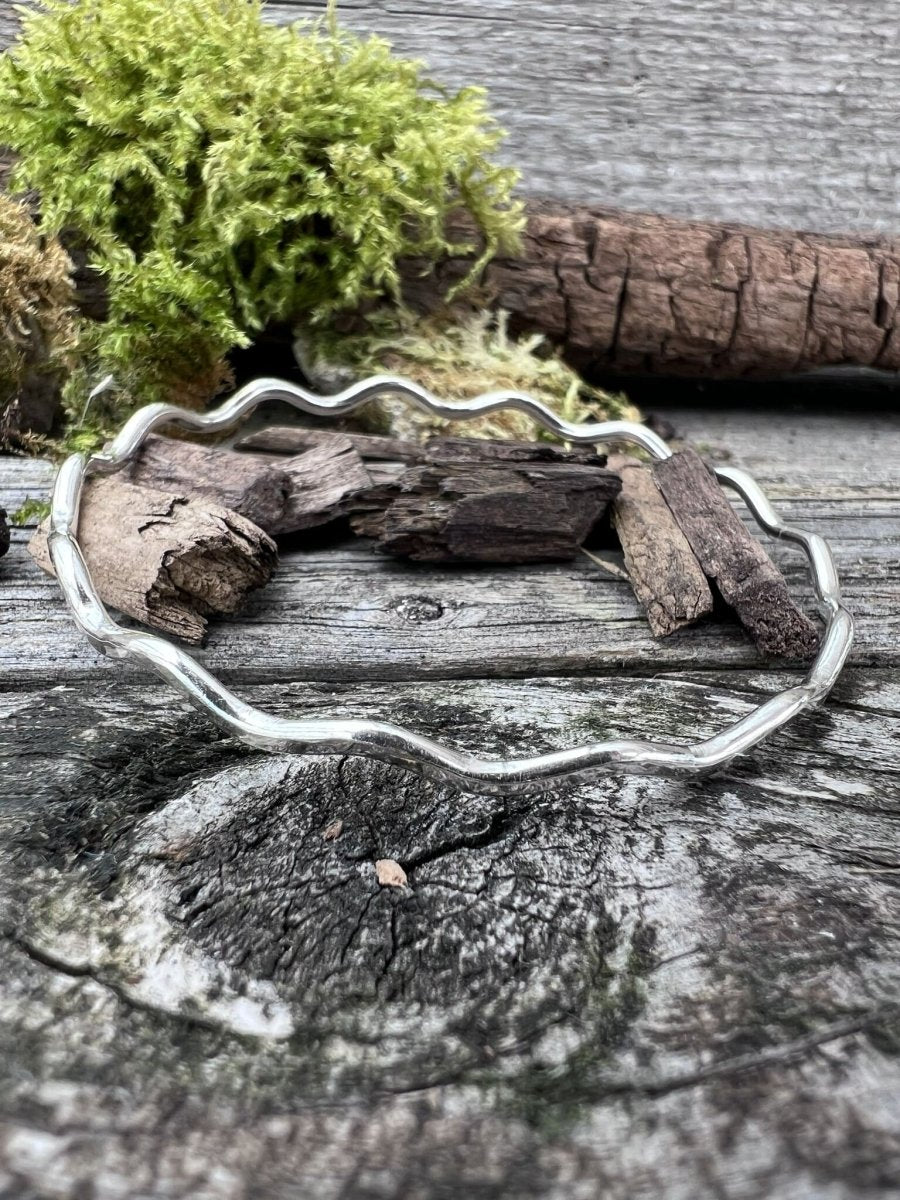 Recycled sterling silver wave bangle 2.5mm on weathered wood with moss, showing the delicate rippled wave-form band