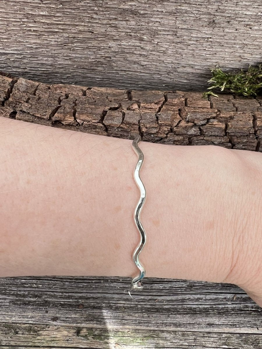 Recycled sterling silver 2.5mm wave bangle worn on a wrist, showing the slim wave band and scale