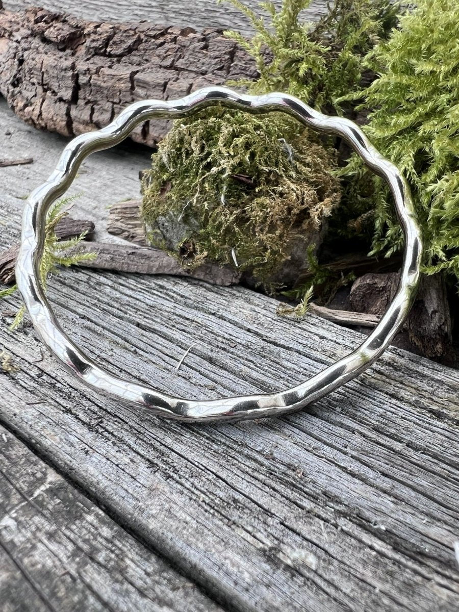 Recycled sterling silver wave bangle 3.5mm on weathered wood with moss, showing the undulating wave-form band