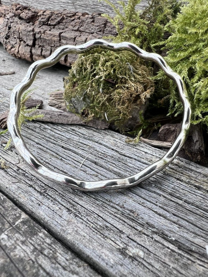 Recycled sterling silver wave bangle 3.5mm on weathered wood with moss, showing the undulating wave-form band