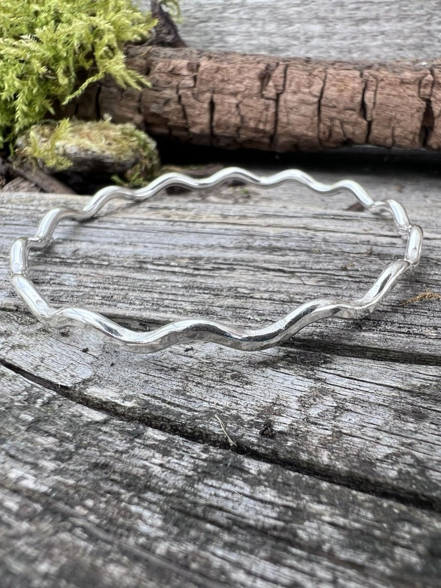 Recycled sterling silver wave bangle 3mm on weathered wood, showing the rippled wave-form band