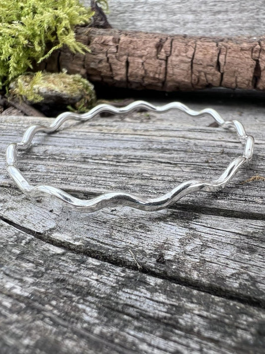Recycled sterling silver wave bangle 3mm on weathered wood, showing the rippled wave-form band