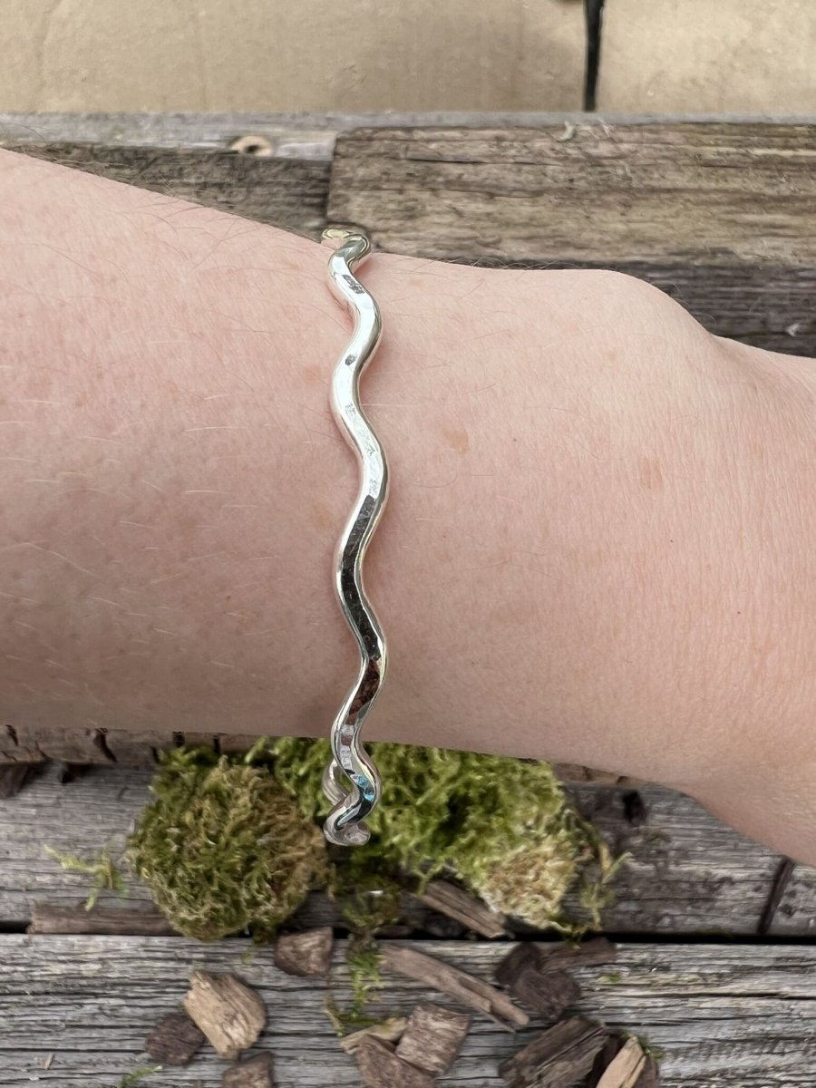 Recycled sterling silver 3mm wave bangle worn on a wrist, showing scale and the flowing wave band