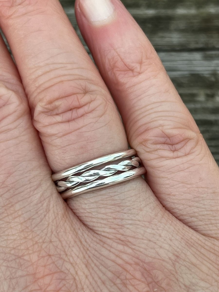 Round twisted sterling silver ring worn on a finger, with plain stacking rings, stacked showing the statement twisted band and scale